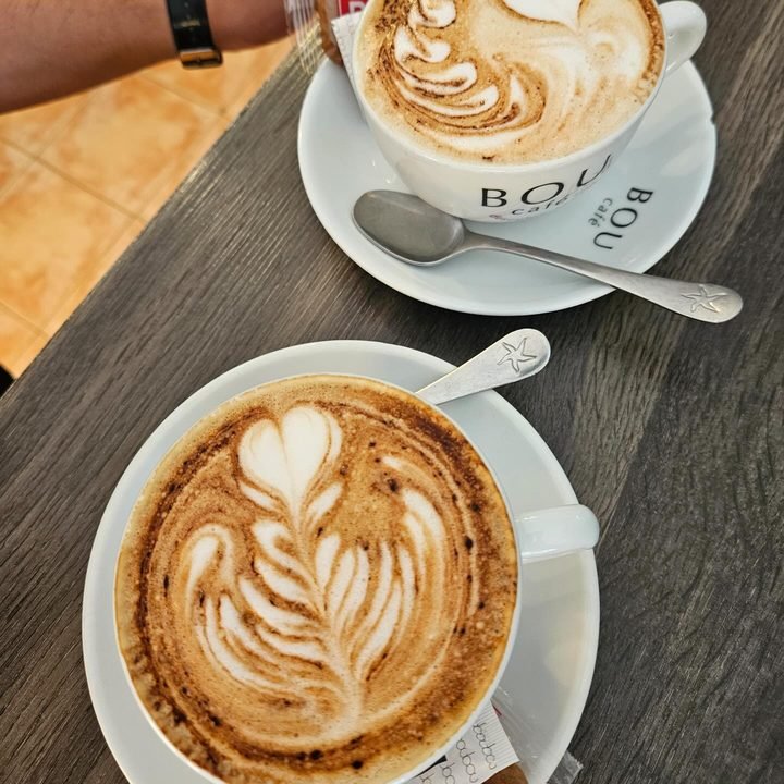 Dos cappuccinos recién servidos en taza y plato sobre la mesa del local.