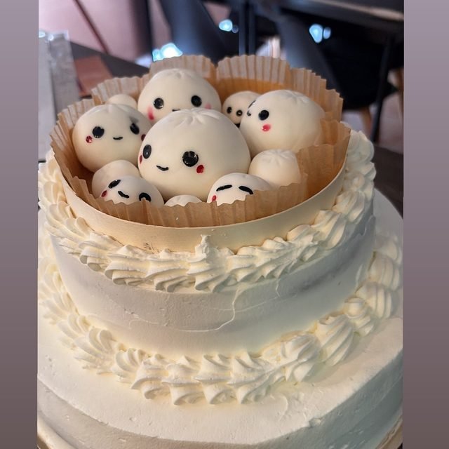 Tarta de dos pisos con nata blanca y figuras de azúcar en la parte superior.