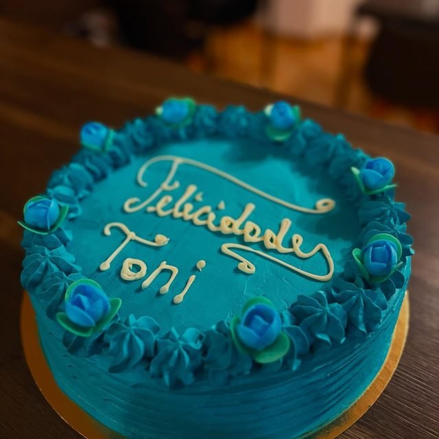 Tarta turquesa con la dedicatoria «Felicidades Toni» escrita a mano en crema.