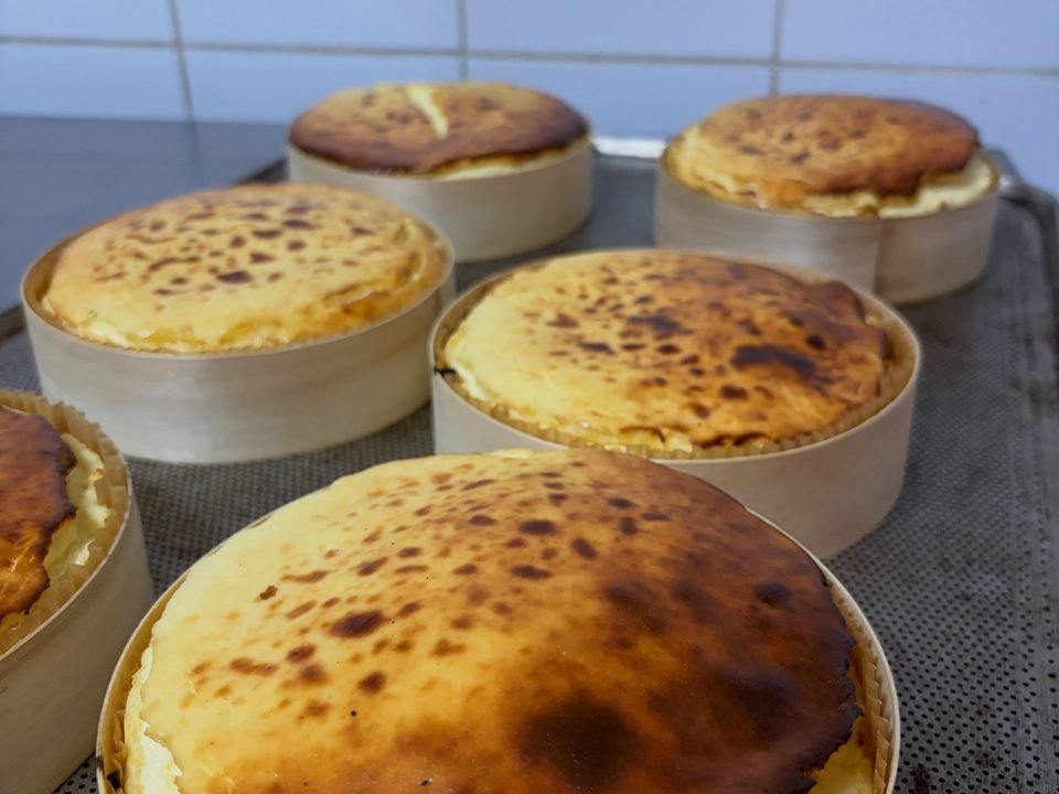 Varias tartas de queso al horno enfriándose sobre la encimera después de salir del horno.