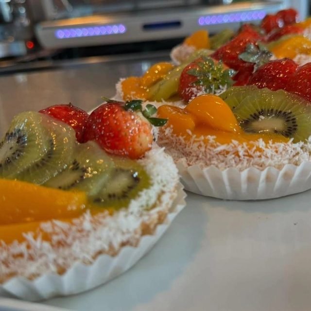 Tartas de fruta con kiwi, fresa y melocotón sobre el mostrador.