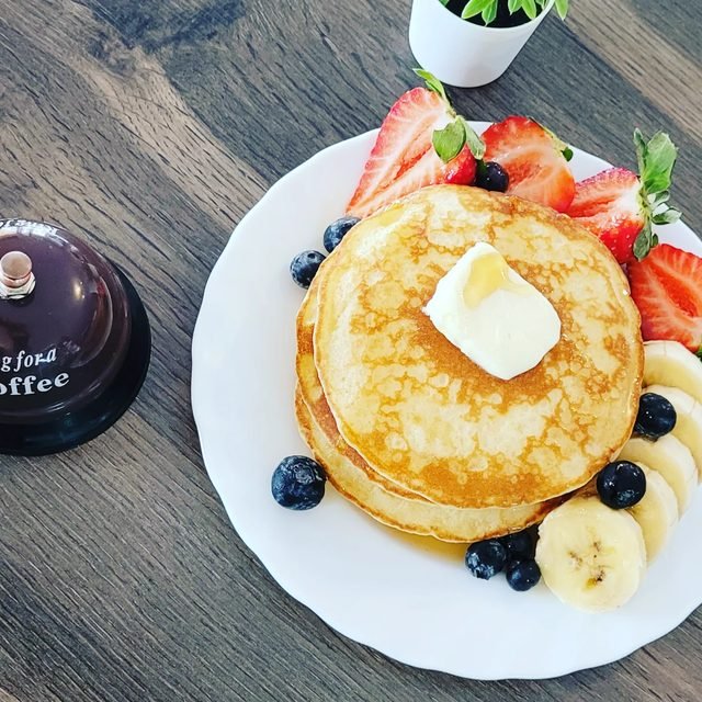Torre de tortitas con mantequilla, fresas, arándanos y plátano.